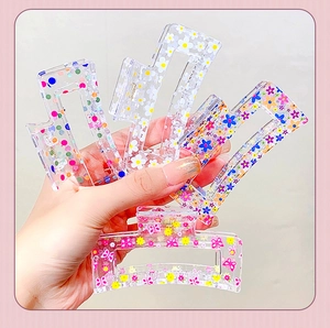 Detailed close-up of four rectangle transparent hair claws with floral and polka dot patterns