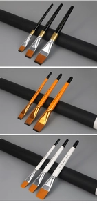 Detailed view of three nylon flat paint brushes in black, orange, and white wooden handles