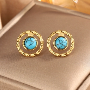 Macro shot of gold-plated twisted earrings featuring turquoise stone in Bohemian vintage style