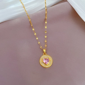 Gros plan d'un collier doré avec pierre rose en forme de cœur et halo étincelant