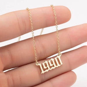 Macro shot of gold-plated 1990 year pendant in gothic font with fine link chain