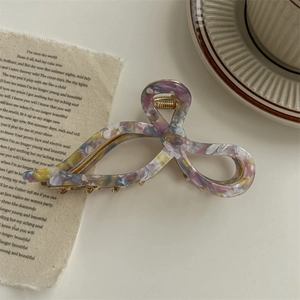 Detailed macro view of high-quality acetate hair claw clip with golden metal spring