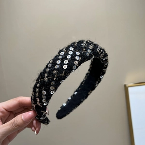Detailed close-up of a woven black headband featuring silver sequins and gold thread accents