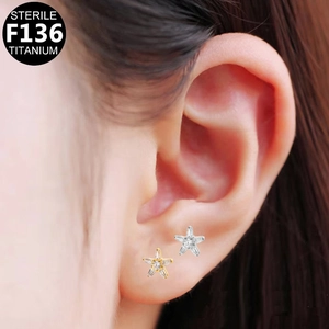 Macro shot of gold and silver F136 titanium star ear studs worn on ear lobe