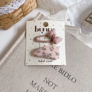 Detail of pink floral fabric snap clip and bow hairpin with pearls on display card