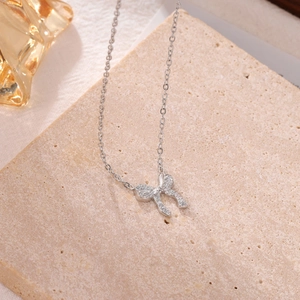 Elegant silver bow pendant necklace with white zircons on a textured stone base