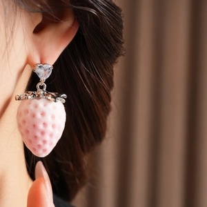 Close-up of pink strawberry earring with heart crystal worn on a model in soft lighting