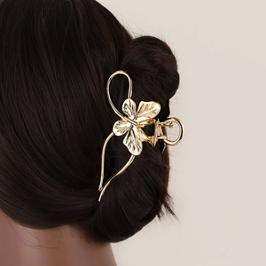 Elegant gold metal butterfly hair claw clip with leaf design on dark hair back view