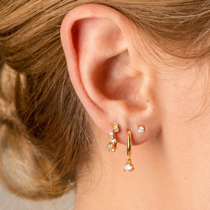 Close-up of gold earring set with zircon stones showing stacked ear styling on model