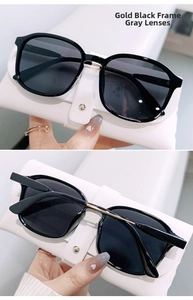 Close-up of black and gold frame sunglasses with gray lenses and a white leather pouch