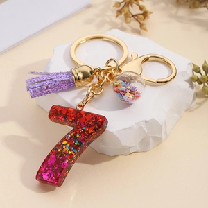 Detail of red glitter number 7 keychain with purple tassel and colorful star pendant