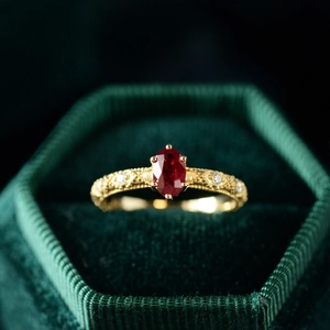 Macro shot of an oval red ruby ring with gold plating on a green velvet box