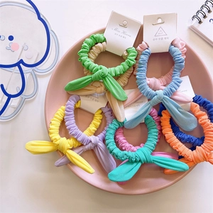 Pastel rabbit ear scrunchies set in colorful macaron tones on a pink decorative plate