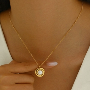 Close-up of elegant gold necklace with triple-ring pendant and white pearl on model