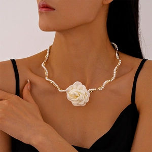 Close-up of golden metal chain intertwined with pearls and a white fabric floral pendant
