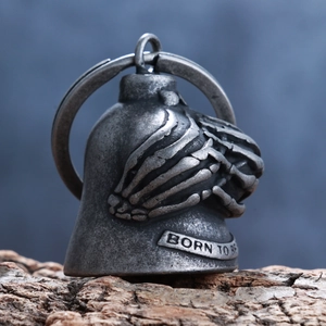 Macro shot of retro metal bell keychain featuring skull hand design and BORN TO BE engraving