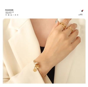 Close-up of gold plated stainless steel heart bracelet and rings on woman's hand
