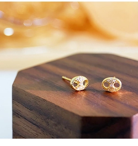 Macro shot of gold pig nose stud earrings with white pavé cubic zirconia on wood