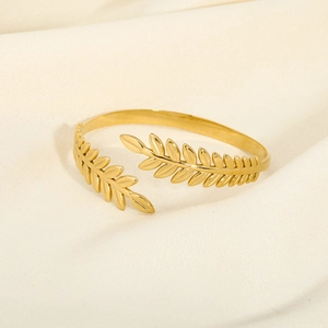 Detailed close-up of a gold-plated olive leaf open cuff bracelet on silk fabric