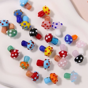 Colorful handmade glass mushroom beads for DIY jewelry making on a white ceramic plate