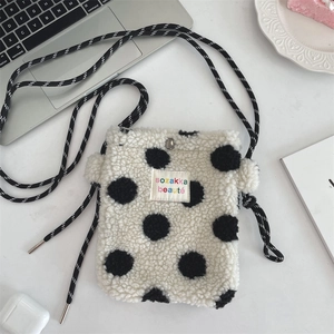 Gros plan sur le sac en peluche à pois noirs et blancs avec bandoulière tissée