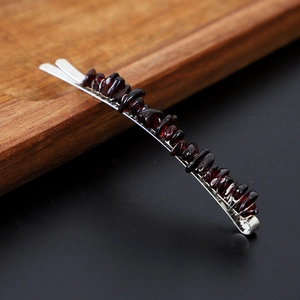 Detailed close-up of dark red crystal stone beads on a silver metallic hair clip