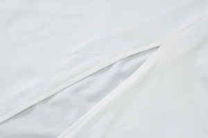 Close-up detail of smooth white fabric texture and precision slit stitching of the dress