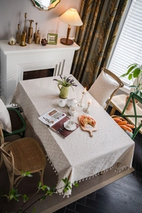 Detail of linen tablecloth with daisy floral patterns and decorative tassels edges