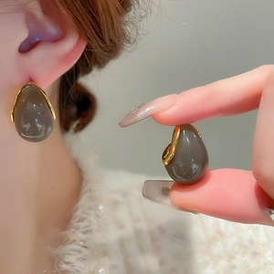 Vue détaillée des boucles d'oreilles en résine ambrée avec bordure métallique dorée