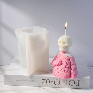 Detail of mummy skull candle silicone mold with a pink wax sample on a white book