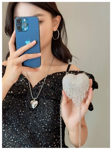 Detailed shot of a silver heart-shaped evening bag with sparkling rhinestones and tassels