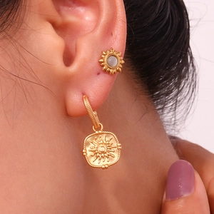 Vintage golden sunburst stud and square star embossed earrings worn by a model