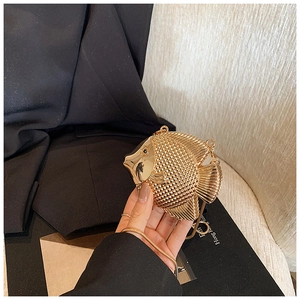 Detailed view of fish-shaped gold metal evening clutch with scale texture and chain