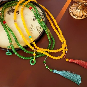 Détail de colliers en perles avec glands vert jade et jaune ambre sur un éventail