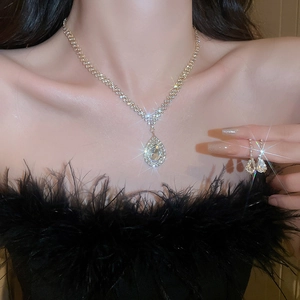 Dettaglio del set di collana e orecchini a goccia dorati con strass su modella