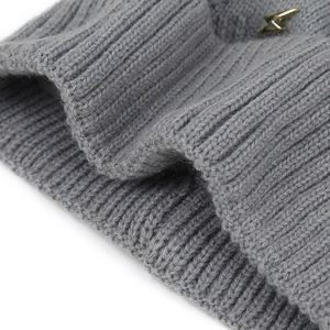 Detail of grey rib-knit winter hat with soft wool texture and golden lightning pin