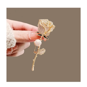 Exquisite Rosenbrosche mit rosa Kristallblättern, grünen Blättern und einer weißen Perle