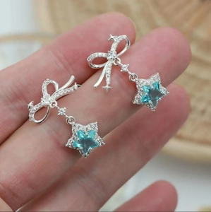 Macro detail of silver bow earrings with teal star crystal and shimmering zircon accents