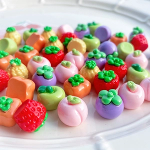 Vista macro di frutta in miniatura assortita in resina tra cui fragola e pesca per il fai da te