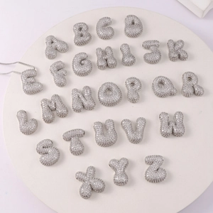 Macro shot of 26 silver bubble initial pendants with pavé-set clear cubic zirconia stones