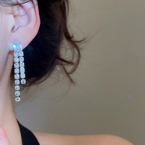Detailed close-up of sparkling zircon tassel earrings worn by a model in luxury style