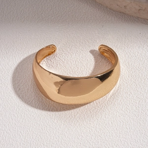 Detailed view of wide 18k gold plated domed cuff bangle on white textured stone