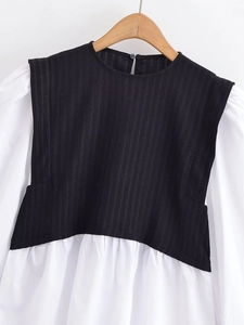 Détail de couture contrastée et manches longues sur un haut bicolore noir et blanc