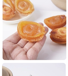 Macro view of a realistic golden dried abalone food model held in hand for size comparison
