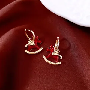 Exquisite rocking horse earrings set with red enamel and crystals on red silk fabric