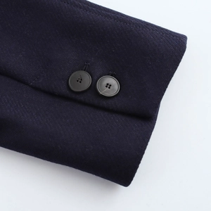 Close-up of dark blue wool coat cuffs featuring two black round buttons on white background
