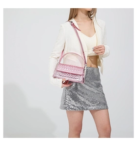 Metallic pink handbag with crocodile texture shown with elegant cream outfit and silver skirt