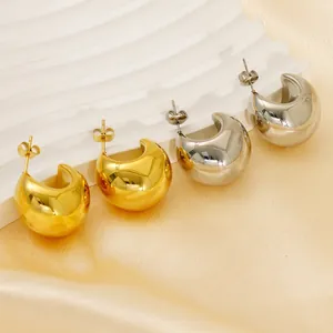 Polished gold and silver chunky hoop earrings displayed on a white textured stand