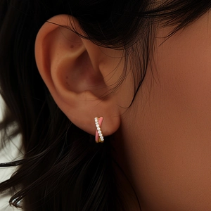 Close-up of pink enamel and zircon pavé cross hoop earrings worn on a model's ear