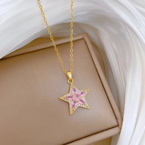 Collier en titane doré avec pendentif étoile rose et zircons sur boîte à bijoux